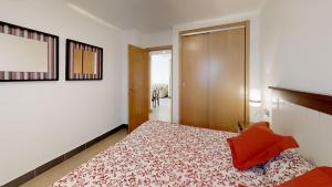 a bedroom with a bed with a red pillow on it at Leo Punta Umbría in Punta Umbría