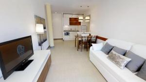 a living room with a white couch and a television at Leo Punta Umbría in Punta Umbría