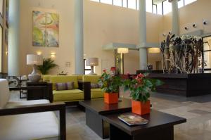 a lobby with a yellow couch and tables with plants at Leo Punta Umbría in Punta Umbría