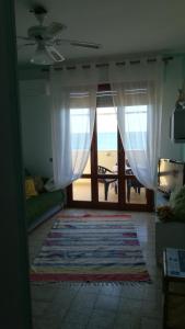 ein Wohnzimmer mit einem Fenster mit Blick auf den Strand in der Unterkunft Alba Apartment in Laigueglia