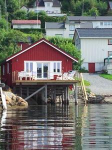 a red house sitting on a dock in the water at The Boathouse in Råkvåg