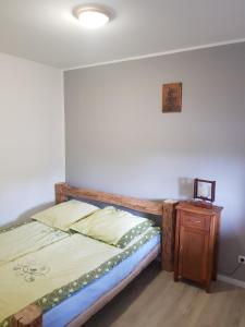a bed in a room with a wooden bed frame and a table at Agroturystyka Karczma nad Jarem Mierzejewo in Mierzejewo