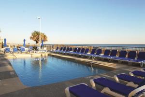 a pool with chairs and the ocean in the background at Seaside Resort by Capital Vacations in Myrtle Beach