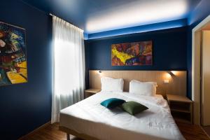 a blue bedroom with a large bed with two pillows at Albergo Residenza Al Teatro in Udine