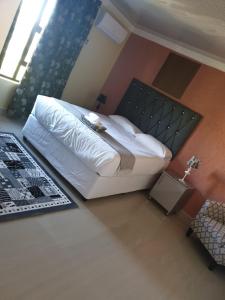 een slaapkamer met een bed met een witte sprei bij MATAT GARDENS in Matatiele