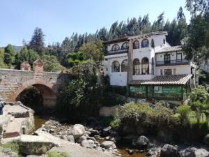 a building next to a river with a bridge at Hotel Calicanto Real Cafe Museo in Monguí