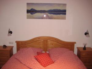 a bed with two red pillows and a picture on the wall at Landhotel zum Staffelwirt in Jachenau