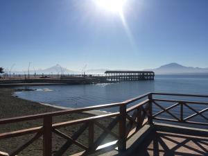 a pier on the water with the sun in the background at Hospedaje Lago Llanquihue in Llanquihue