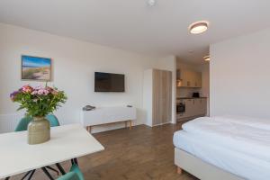 ein Schlafzimmer mit einem Bett und einem Tisch mit Blumen darauf in der Unterkunft Aparthotel Zoutelande Luxe Studio 2 personen (huisdieren toegestaan) in Zoutelande