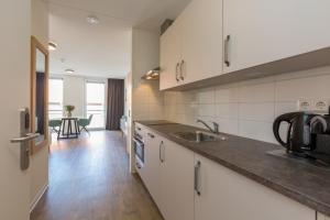 een keuken met witte kasten, een wastafel en een tafel bij Welcome in - Aparthotel Zoutelande Luxe Studio 2 personen - 1 huisdier toegestaan in Zoutelande +4 foto's