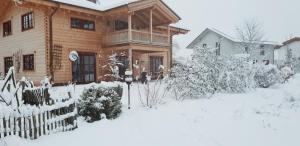 een huis bedekt met sneeuw met een hek bij Ferienwohnung im gemütlichen Blockhaus vor den Bergen in Wielenbach