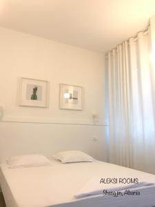 a white bedroom with a bed and a window at Aleksi rooms in Shëngjin
