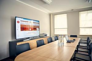 a conference room with a large projection screen and a table and chairs at Bed&Breakfast Erber in Ismaning