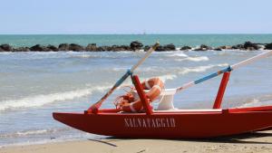 a woman laying in a boat on the beach at Hotel Tritone Rimini in Rimini
