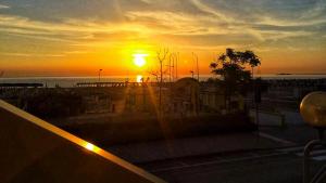 a sunset with the sun setting over the water at Hotel Tritone Rimini in Rimini