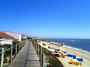 a boardwalk leading to a beach with colorful umbrellas at Casa Ferreira in Vila Chã