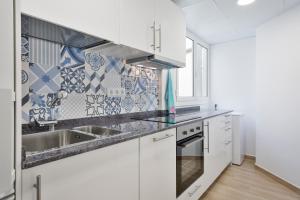 a kitchen with white cabinets and blue and white tiles at Pis Ocata in El Masnou