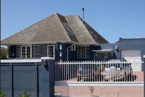 a blue house with a fence in front of it at Milnerton Cottage in Cape Town