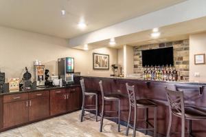 un bar avec tabourets de bar en bois et télévision dans l'établissement Cobblestone Inn & Suites - Bridgeport, à Bridgeport