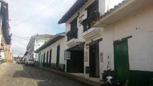 una calle estrecha con edificios con puertas verdes y un coche en Hotel Casa Suite Curiti, en Curití