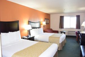 a hotel room with two beds and a desk at Travelodge by Wyndham, Newberg in Newberg