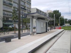 een bushalte met banken voor een gebouw bij Très joli appartement mignon confortable à Paris Villeneuve-la-Garenne in Villeneuve-la-Garenne