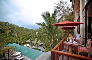 a man sitting at a table on the balcony of a resort at Komaneka at Bisma Ubud in Ubud