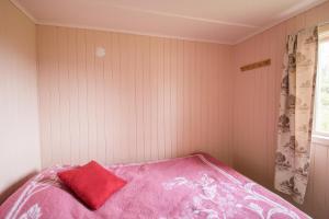 a bedroom with a pink bed with a red pillow at Midt Troms Perle in Finnsnes