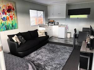 a living room with a black couch and a kitchen at Pacific Harbour Lodge in Whangaroa