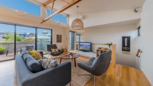 a living room with a couch and chairs and a tv at Luxe Townhouse - WiFi included in Inverloch
