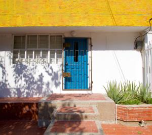 a blue door on a house with a yellow roof at QuillaHost Tropical Apartment in Barranquilla