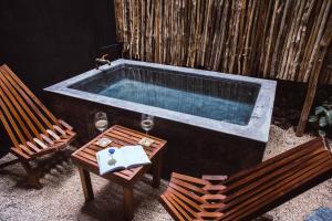 a pool with a chair and a tub in it at Aroma Tulum in Tulum
