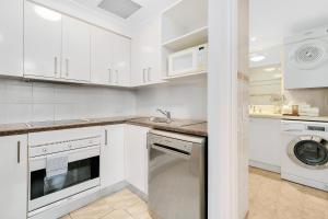 a kitchen with white cabinets and white appliances at Manor Apartment Hotel in Brisbane