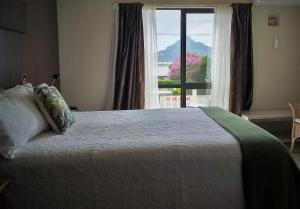 a bedroom with a large bed with a window at Harbour View Bed & Breakfast in Tairua