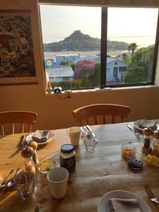 a table with a view of the ocean from a window at Harbour View Bed & Breakfast in Tairua