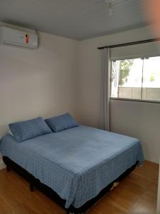 1 dormitorio con cama con sábanas azules y ventana en Quitinete Balneário en Balneario Camboriú