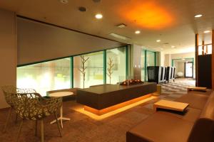 una hall con tavolo e sedie in un edificio di Kusatsu Now Resort Hotel a Kusatsu