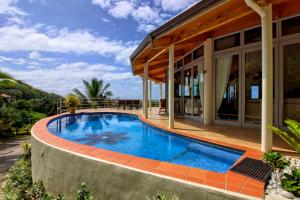 a swimming pool in front of a house at Villa Maria in Rarotonga