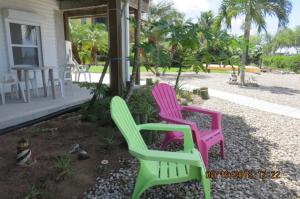 three colorful chairs sitting outside of a house at Bayview BnB in Matlacha