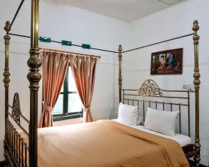 una camera con letto a baldacchino e finestra di nDalem Gamelan a Yogyakarta