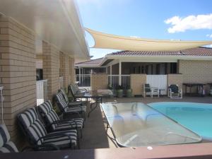 a patio with lounge chairs and a swimming pool at Top of the Town Motel in Inverell