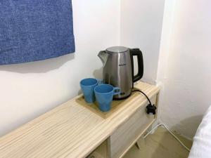 a coffee pot and two blue cups on a wooden shelf at The Cove Hostel - Tong Fuk Octopus in Hong Kong