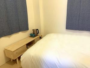 Un pequeño dormitorio con una cama blanca y una mesa de madera. en The Cove Hostel - Tong Fuk Octopus en Hong Kong