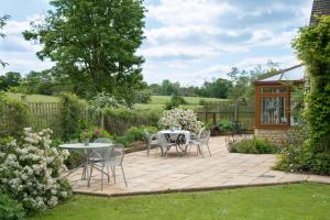eine Terrasse mit einem Tisch und Stühlen im Garten in der Unterkunft Kingfisher Cottage in Winchcombe