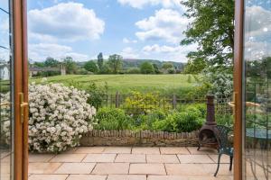 einen Blick auf den Garten von einer Glastür mit einer Bank und Blumen in der Unterkunft Kingfisher Cottage in Winchcombe + 31 Fotos