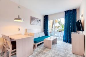 een kleine woonkamer met een tafel en een bank bij Palm Garden in Port d'Alcudia