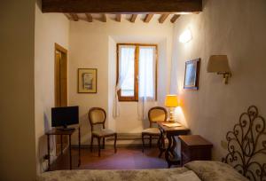 a bedroom with a bed and chairs and a television at Locanda Il Pino in San Gimignano