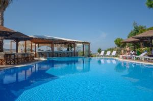 a large blue swimming pool with chairs and umbrellas at Alkyoni Beach Hotel in Naxos Chora