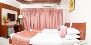 Habitación de hotel con 2 camas y TV en Chola Serviced Apartment, en Tiruchchirāppalli