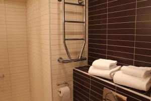 un bagno con pareti piastrellate di nero e asciugamani bianchi di Hotell Åsen ad Anderstorp